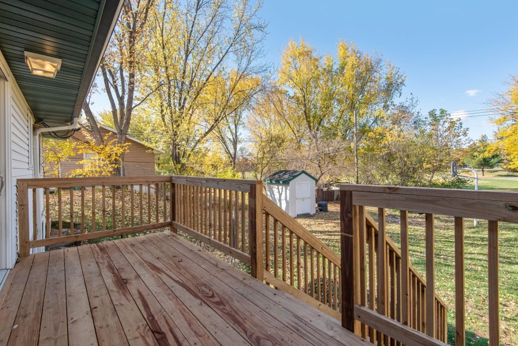 Spacious wooden backyard deck overlooking an autumn yard