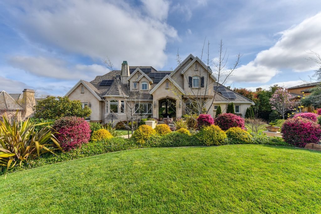 Large home with lush, colorful landscaped front yard
